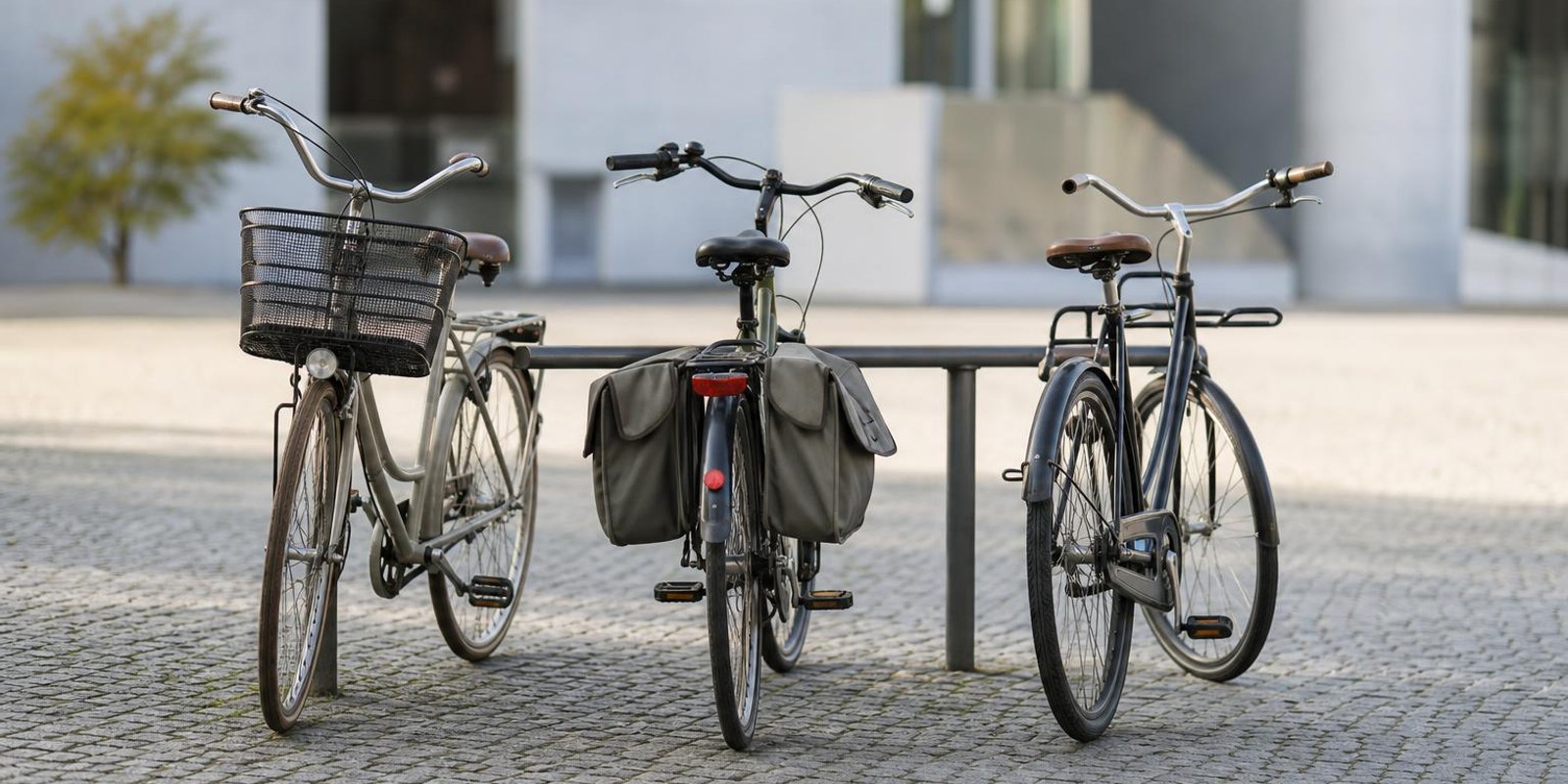 Drei unterschiedliche Alltagsraeder stehen nebeneinander am Fahrradstaender auf einem Platz.