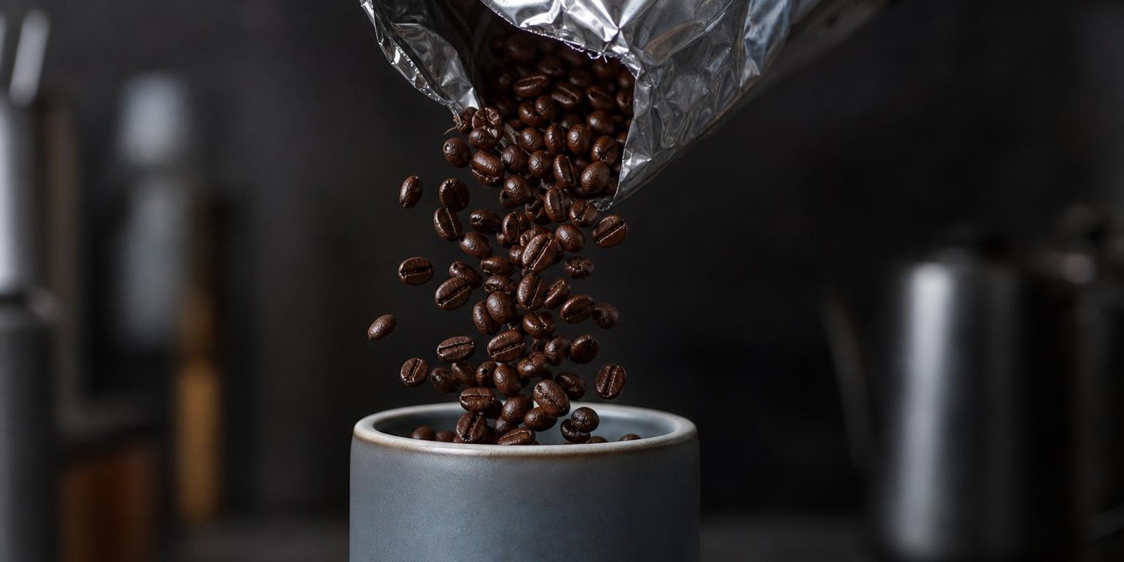 Kaffeebohnen fallen aus einem Beutel in eine Keramikdose mit Dichtungsdeckel.