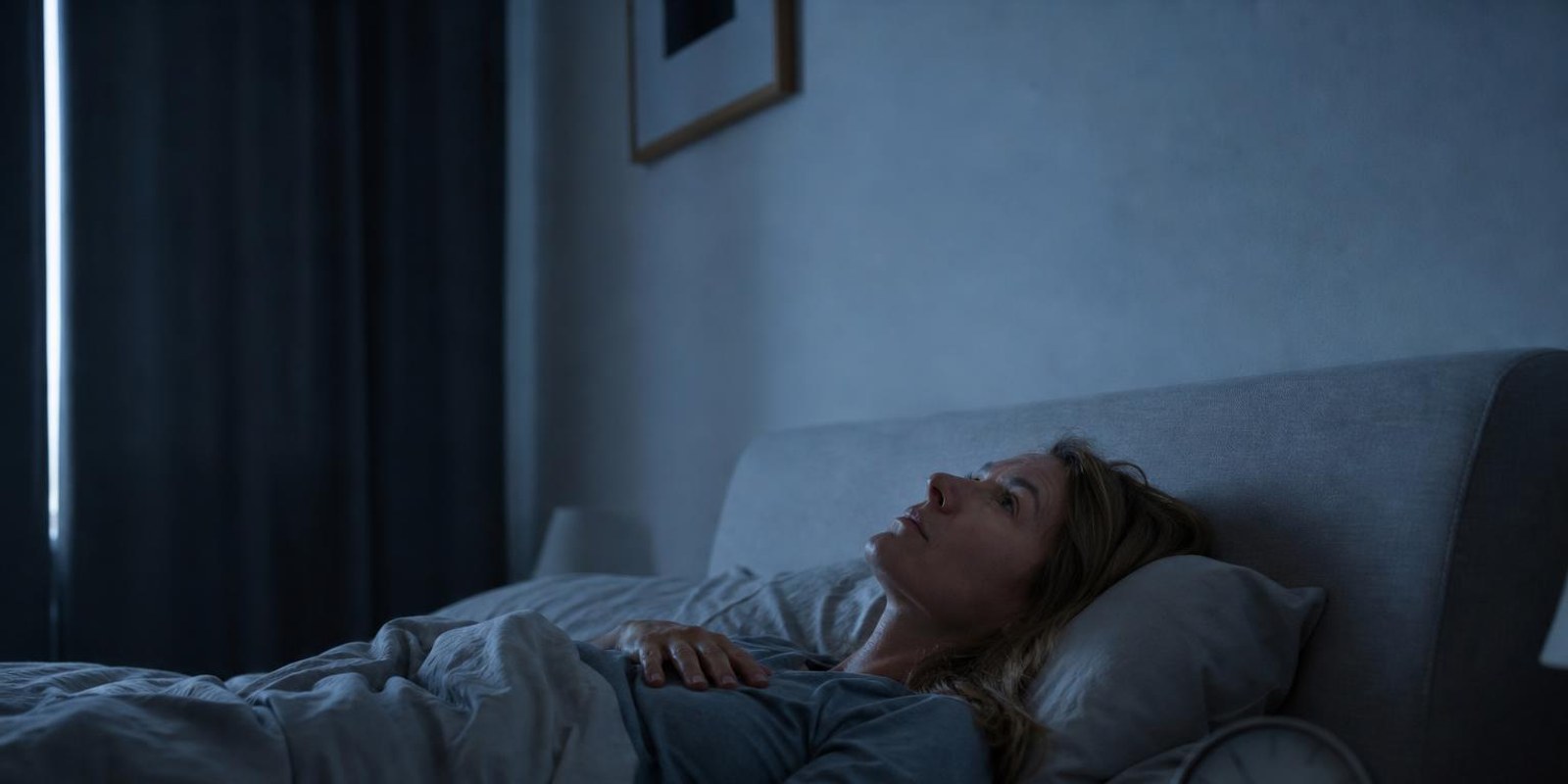 Frau liegt mitten in der Nacht wach im Bett und starrt an die Zimmerdecke.