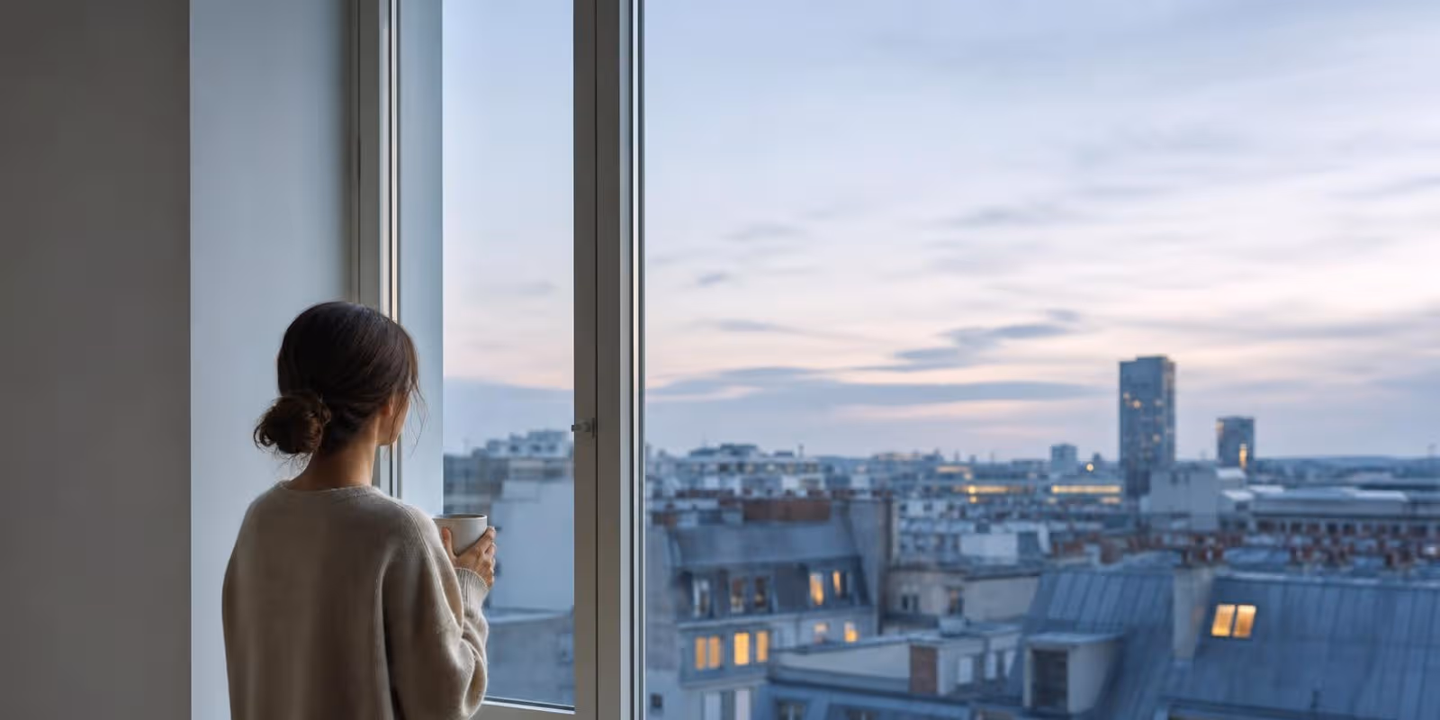 Aquarell: Person steht mit einer Tasse am breiten Fenster, auf der Bank liegen Notizbuch und Buecher.